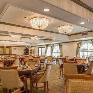An elegant dining room with chandeliers, tables, and chairs arranged for guests.