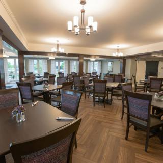 An empty dining room with neatly arranged tables and chairs under warm lighting.