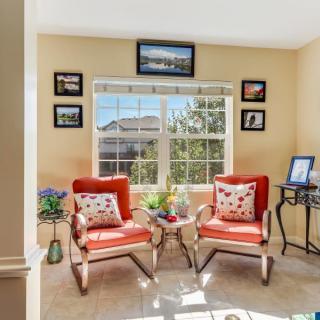 A cozy living room with two bright orange chairs facing a window, surrounded by decor and natural light.
