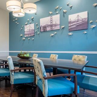 A modern dining room with blue walls, adorned with wall art and decorative fish accents.