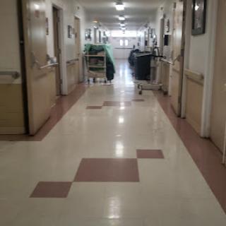 A view down a hospital hallway, showcasing patient rooms and medical equipment.