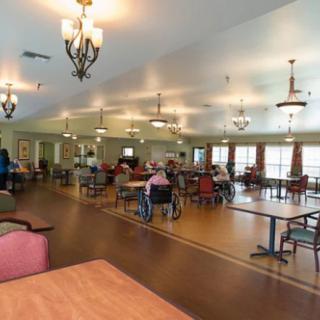 A spacious dining area in a senior living facility with residents seated at tables.