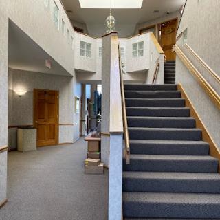 A spacious and welcoming entrance with a carpeted staircase and natural light illuminating the space.