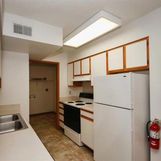 A compact apartment kitchen with essential appliances and white cabinets.