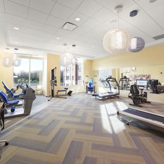 A well-lit gym with various exercise equipment and treadmills.