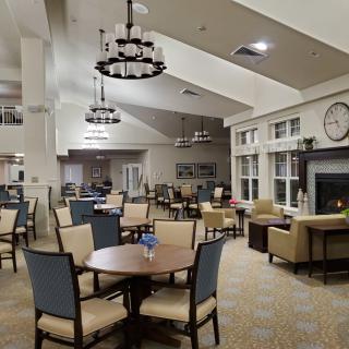 A spacious and elegantly designed dining area with multiple tables and chairs, complemented by stylish ceiling lighting.