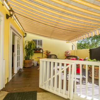 A cozy patio with an awning, featuring outdoor seating and vibrant yellow walls.