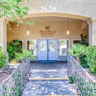 Entrance to a building with a landscaped walkway and greenery.