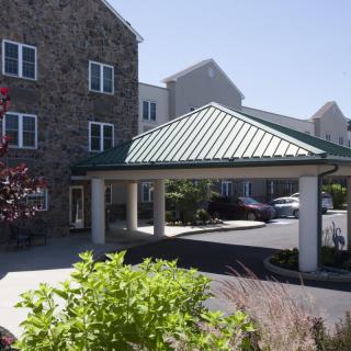A building with a covered entrance and landscaped surroundings.