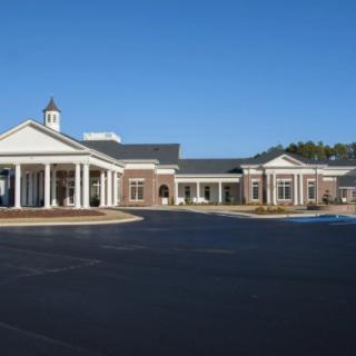 A large building with a traditional architectural style featuring columns and a cupola, set against a clear blue sky.