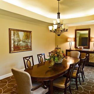 A well-decorated dining room featuring a wooden table with chairs, a chandelier, and a framed painting on the wall.