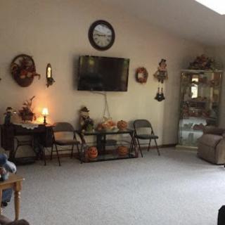 A cozy living room featuring a wall-mounted television, decorative wall hangings, and comfortable seating.