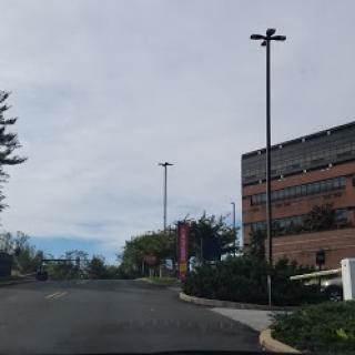 A view of a road leading up to a building under a cloudy sky.