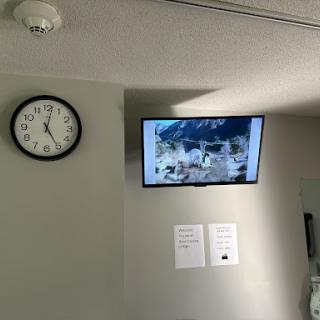 A view of a room featuring a wall clock and a television displaying an image.