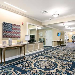 A well-decorated lobby area featuring a large carpet, a table with decorative items, and an American flag artwork on the wall.