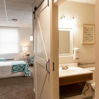 A modern bedroom with an attached bathroom, separated by a stylish barn door.
