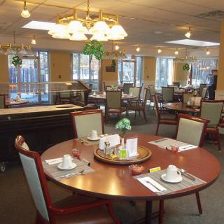 A well-lit dining area with neatly set tables and chairs, featuring elegant decor.