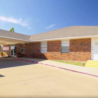 A charming single-story brick residence with a spacious parking area.