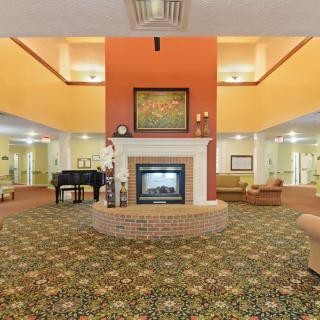A spacious lobby with a central fireplace, surrounded by seating and a piano.