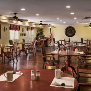 An empty dining room with wooden tables and chairs, featuring an American flag and decor.