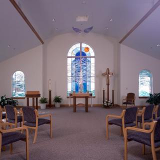 A serene chapel interior with an altar and stained glass windows.