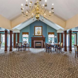 A spacious dining area with elegant decor, featuring a grand chandelier, a fireplace, and vaulted ceilings.