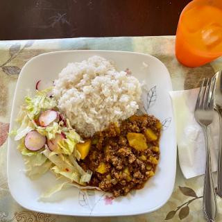 A delicious meal featuring rice, chicken curry with vegetables, and a fresh salad.