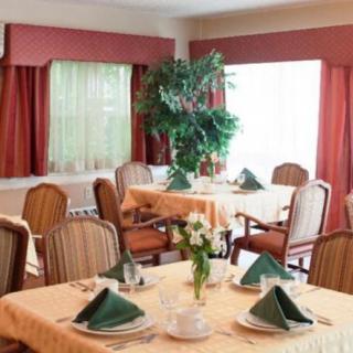 A cozy dining room with neatly arranged tables and green napkins, featuring elegant decor.