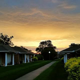 A serene sunset illuminating a quiet pathway lined with buildings.