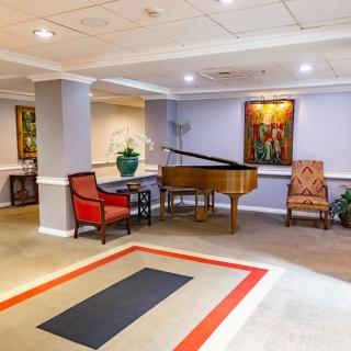 A well-decorated lobby featuring a grand piano, artwork, and comfortable seating.