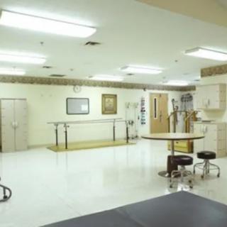 A spacious physical therapy room equipped with medical equipment for rehabilitation and treatment.