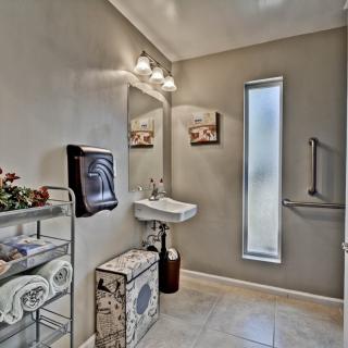 A well-lit bathroom with modern decor, featuring a sink, mirror, and tiled floor.
