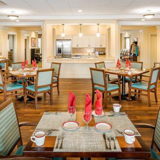 A well-set dining room with neatly arranged tables and chairs, featuring stylish place settings and decorative red napkins.