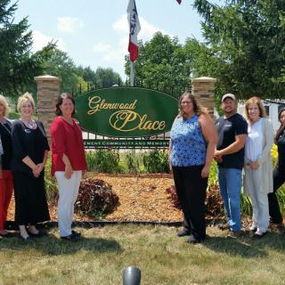 A group of people standing in front of a sign that reads 'Greenwood Place'.