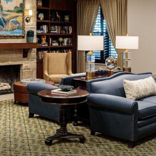 A cozy living room with a sofa, armchair, and fireplace.