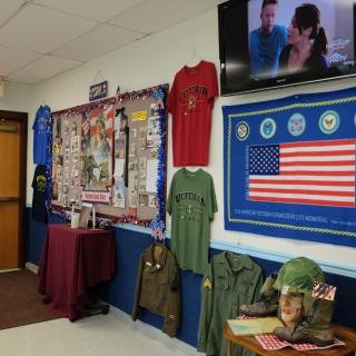 A hallway display featuring military memorabilia, including uniforms, helmets, and an American flag, paying tribute to veterans.