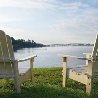 Two chairs overlooking a tranquil lake under a clear sky.