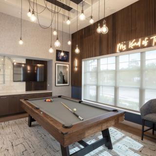A modern game room featuring a pool table with stylish pendant lighting and contemporary decor.