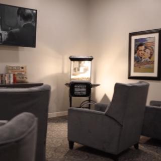 A cozy home theater setup with comfortable chairs, a popcorn machine, and artwork on the walls.