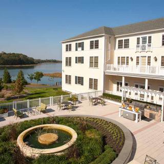 A scenic view of a hotel with a patio overlooking a lake and garden.