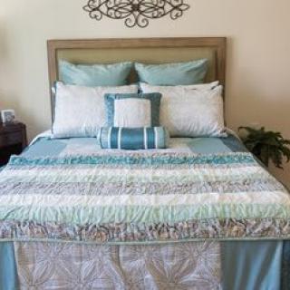 A neatly made bed featuring patterned quilts and decorative pillows in a cozy bedroom.