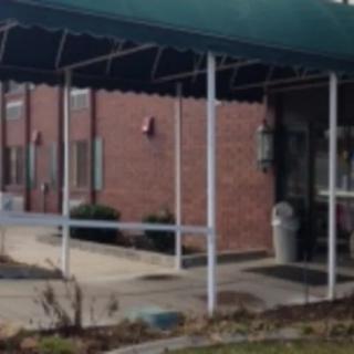 A building entrance with a green awning and brick exterior.