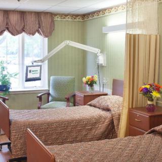 A hospital room with two beds, separated by a curtain, and decorated with flowers.