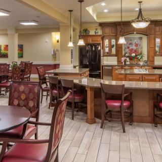 A warmly lit dining and kitchen area with multiple tables and chairs.