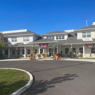 A building with an entrance and driveway, adorned with flags and surrounded by landscaping.