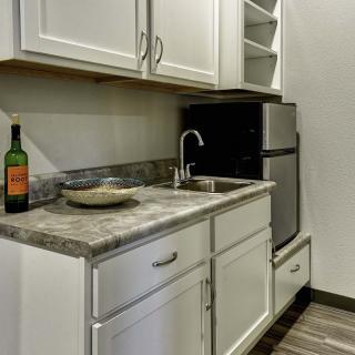 A small kitchen area featuring cabinets, a countertop with a sink, and a refrigerator.