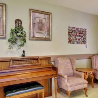 A cozy indoor seating area with a piano and framed artwork on the walls.