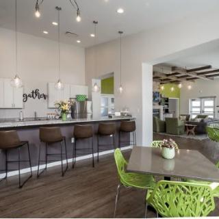 A modern kitchen with bar seating and vibrant green chairs in a spacious open area.