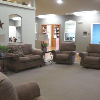 A cozy living room with several beige recliners and sofas, a carpeted floor, and decorative elements.