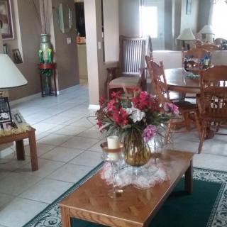 A cozy living room featuring a wooden coffee table with a vase of flowers, surrounded by comfortable seating and home decor.